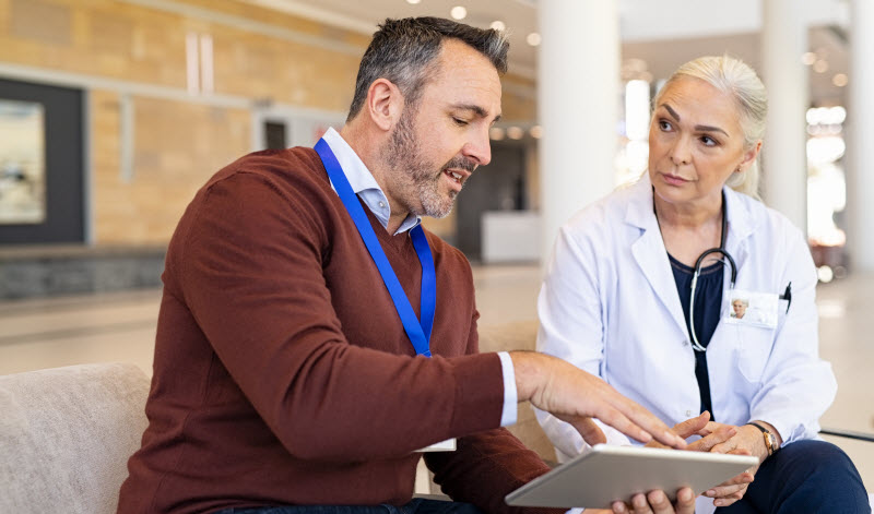 General practitioner discussing patient case status with his medical staff using digital tablet