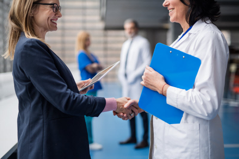 Doctor talking to pharmaceutical sales representative, shaking hands.